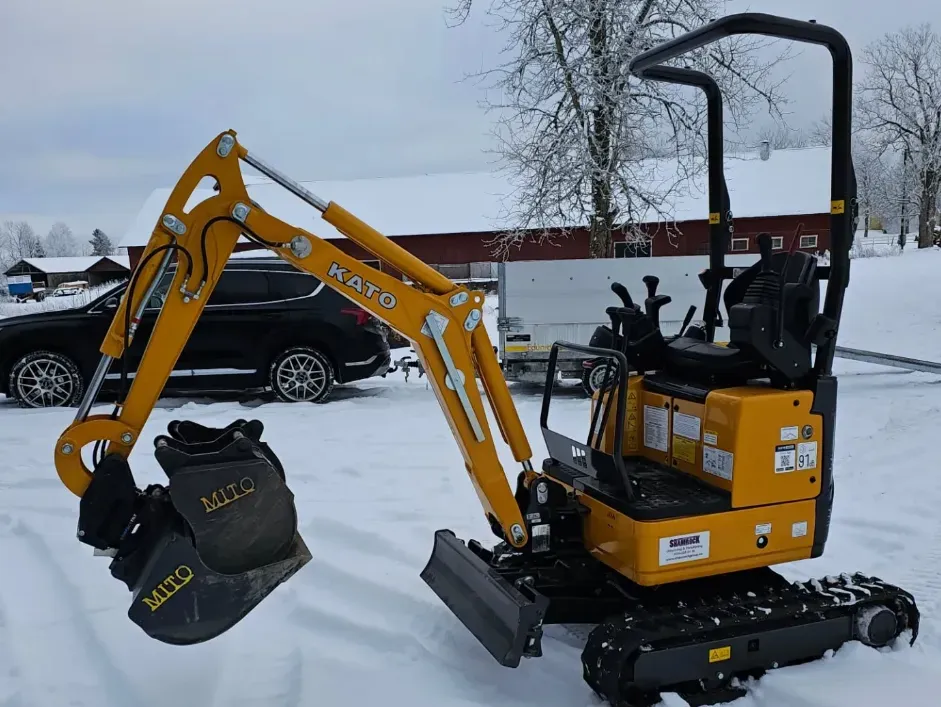 Minigrävare på en snötäckt gårdsplan