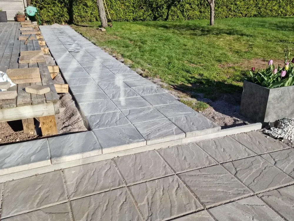 Nylagda betongplattor i en gång vid en gräsmatta