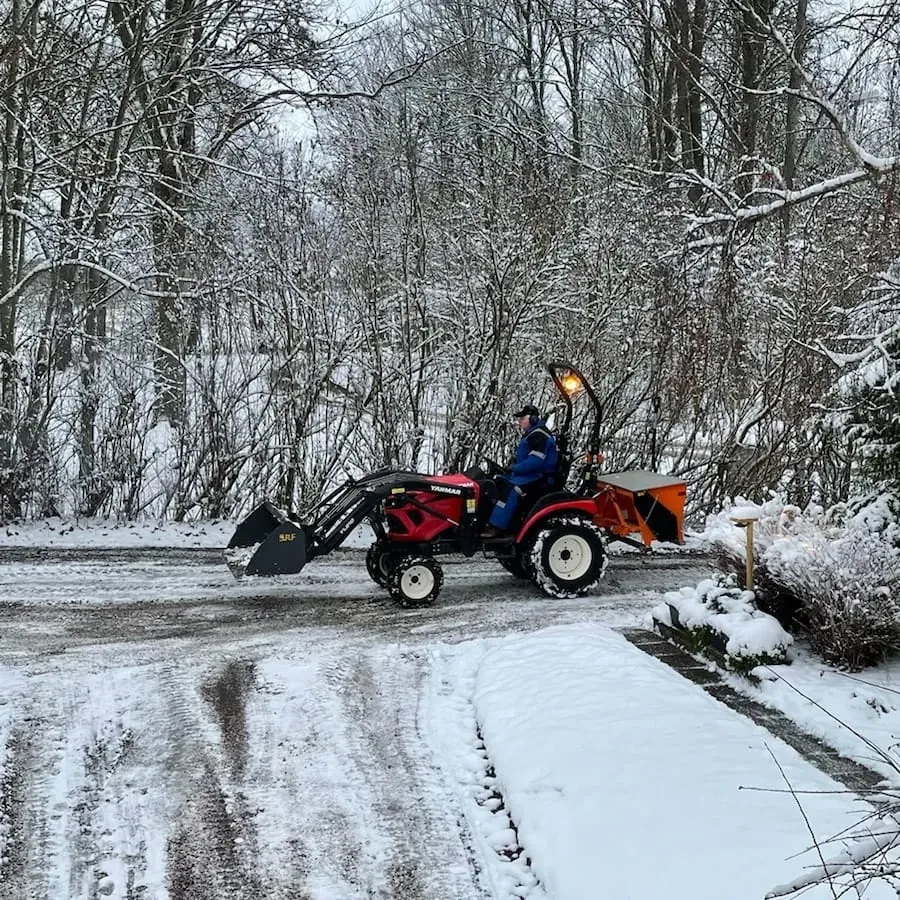 Traktor som röjer snö på en väg i vinterlandskap