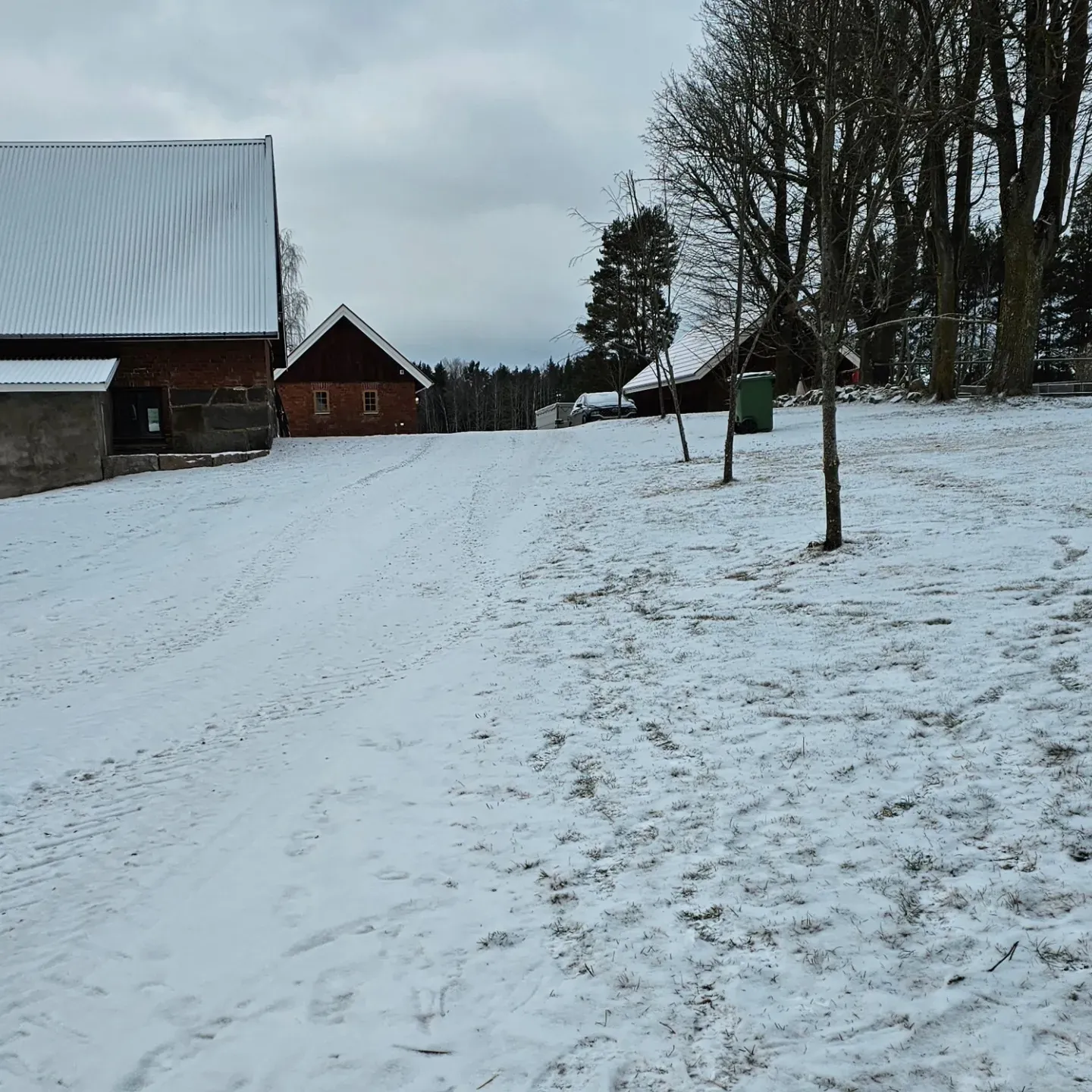 Snötäckt gårdsplan med röda byggnader och kala träd